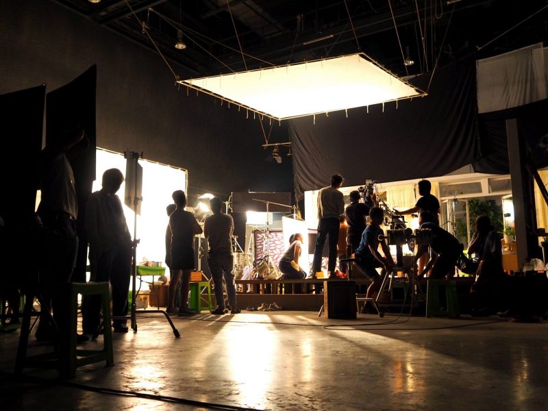 Behind the scenes or the making of film video production and movie crew team working in silhouette of camera and equipment set in studio.